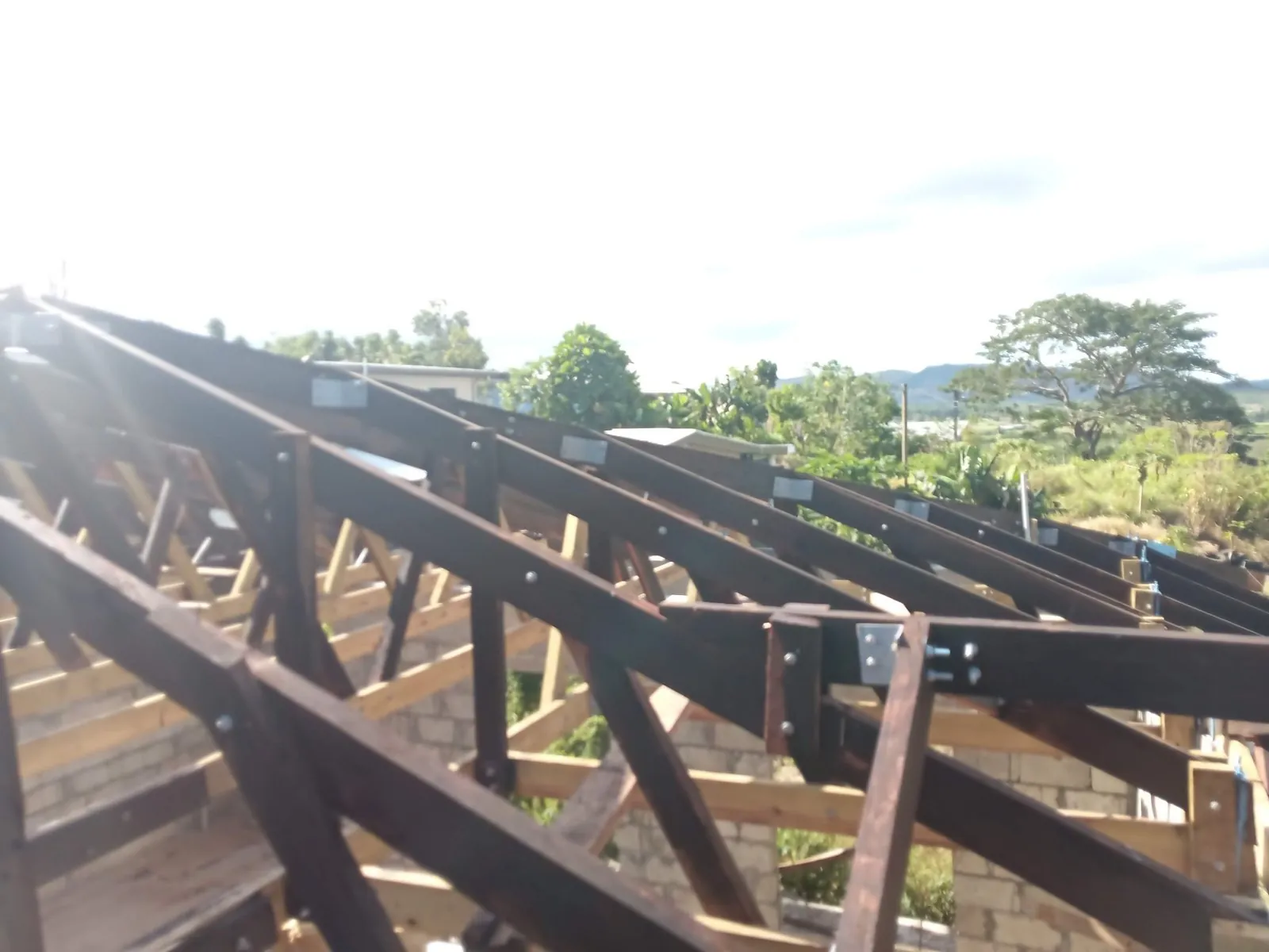 Roof framing on an Othannel build with a completed home behind